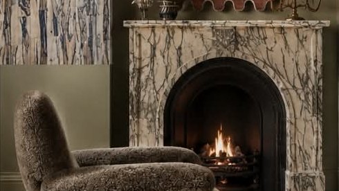 A marble fireplace with a scalloped mirror, shell wall lights and a shearling chair.